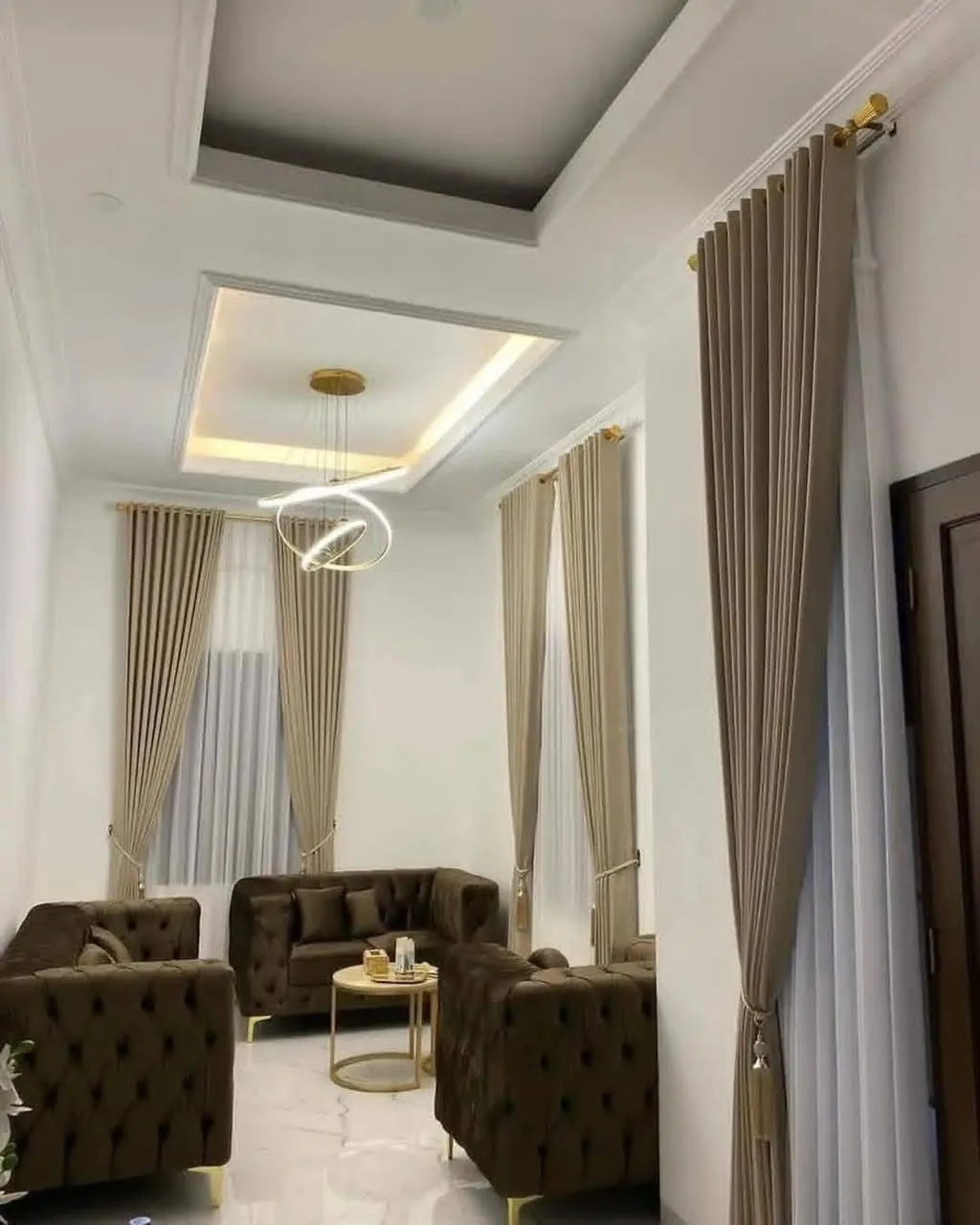 Pemasangan gorden custom krem tinggi dengan vitrase putih di ruang tamu plafon tinggi